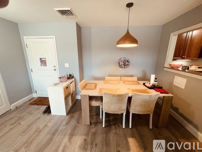 A dining room with a white fridge and a wooden table with chairs.