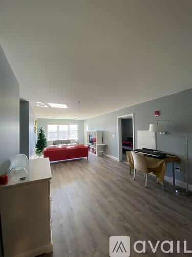 A living room with a red couch and a desk with a computer.
