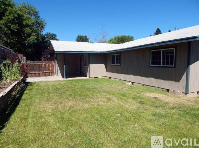 A backyard with a house and a fence.