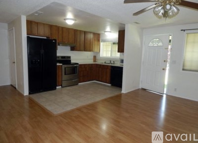 A kitchen with wooden cabinets and a black refrigerator.