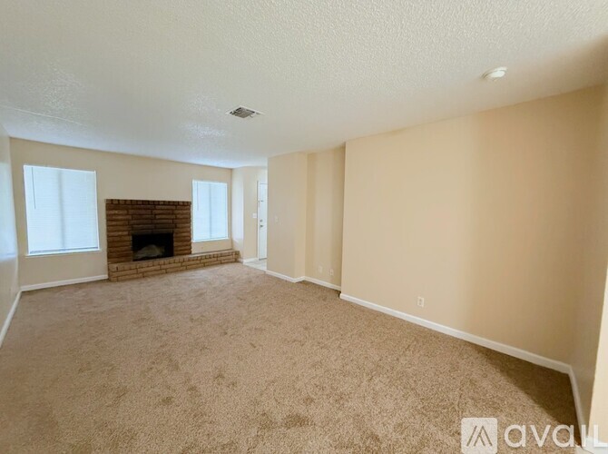 A living room with a fireplace and carpeted floor.