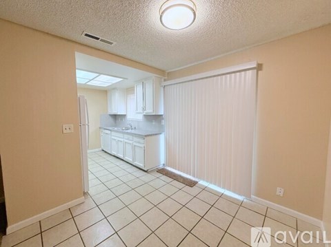 A kitchen with white cabinets and a white refrigerator is shown.