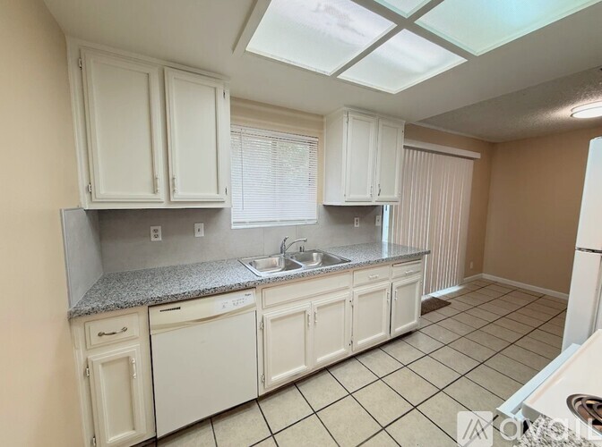 A kitchen with white cabinets and a tiled floor.