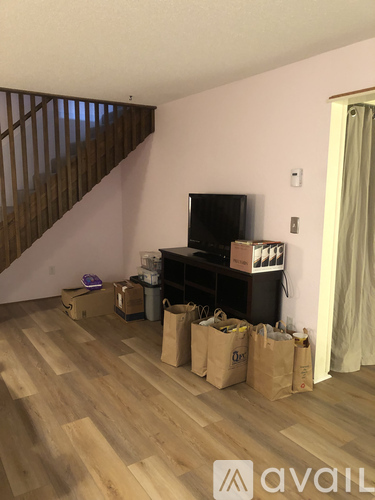 A room with wooden floors and a staircase with a wall-mounted television.