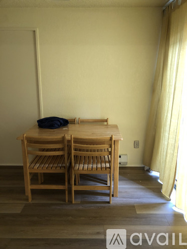 A wooden table with two chairs and a black bag on it.
