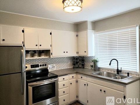 A kitchen with white cabinets and a stainless steel refrigerator.