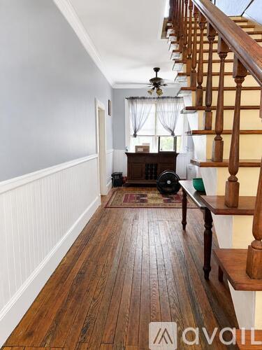 A hallway with wooden floors and a staircase.