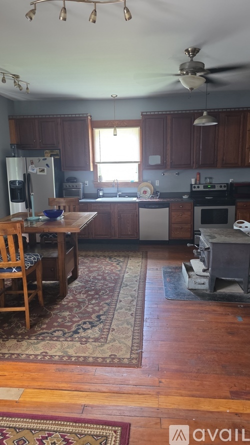 A kitchen with wooden floors and a rug in the middle.