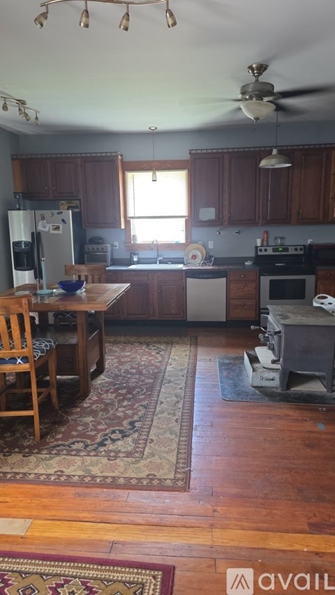 A kitchen with wooden floors and a rug in the middle.