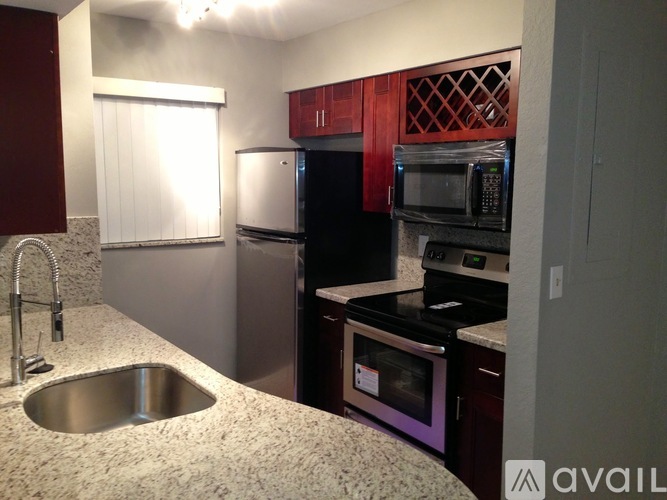 A kitchen with a sink, refrigerator, and microwave.