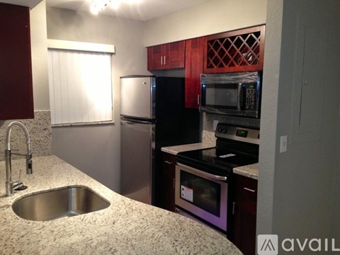 A kitchen with a sink, refrigerator, and microwave.