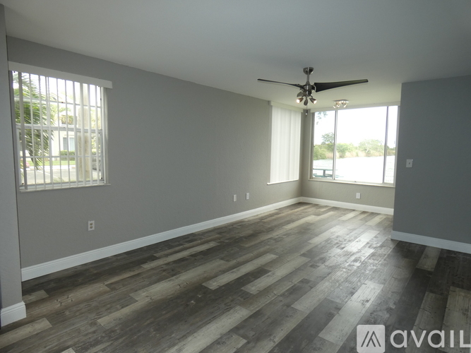 A spacious room with wooden flooring and a ceiling fan.