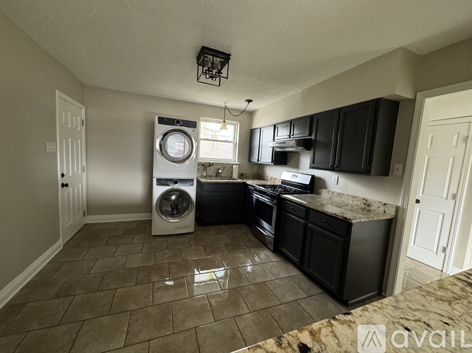 A kitchen with black cabinets and a washer and dryer in the corner.