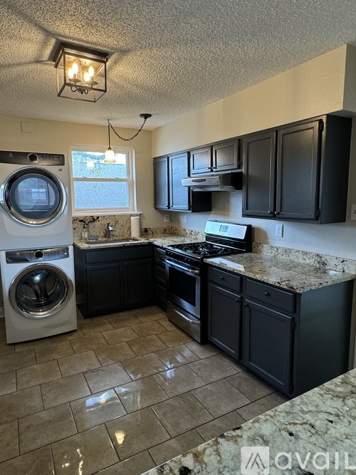 A kitchen with black cabinets and a washing machine.