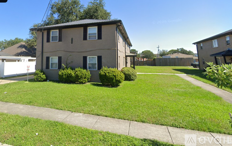 A house with a brown siding and a grey roof with a green lawn in front.