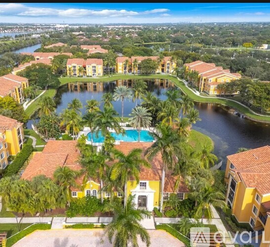 A large building with a pool in the middle of a courtyard surrounded by palm trees.