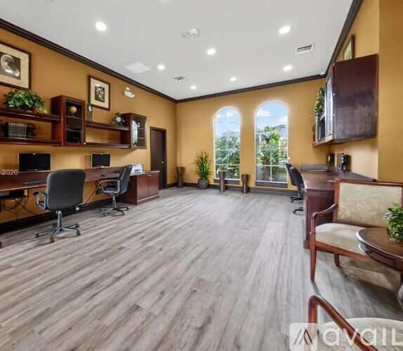 A spacious office room with wooden flooring and a large window.