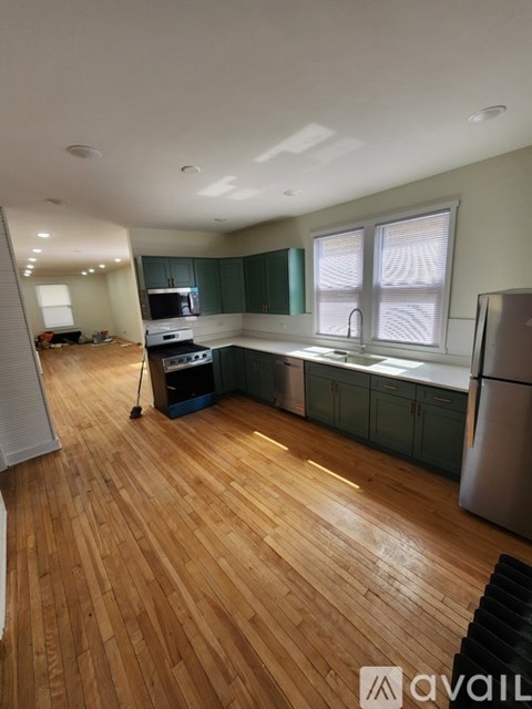 A kitchen with wooden floors and green cabinets.