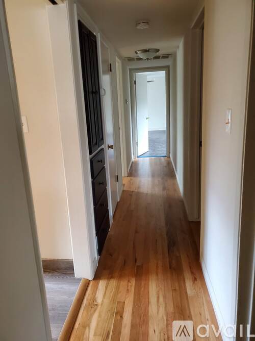 A long hallway with wooden floors and white walls.