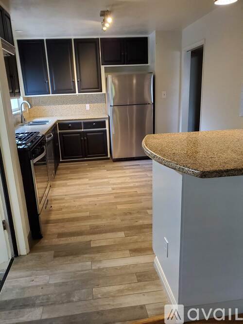 A kitchen with a refrigerator, stove, and cabinets.