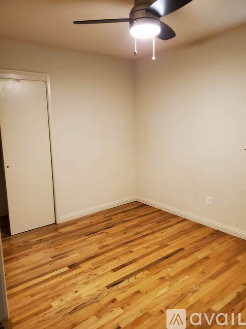 A room with wooden flooring and a ceiling fan.