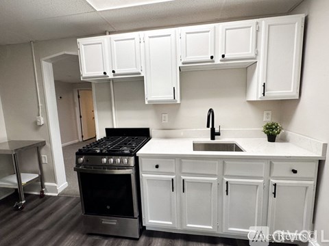 A kitchen with white cabinets and a black stove top oven.