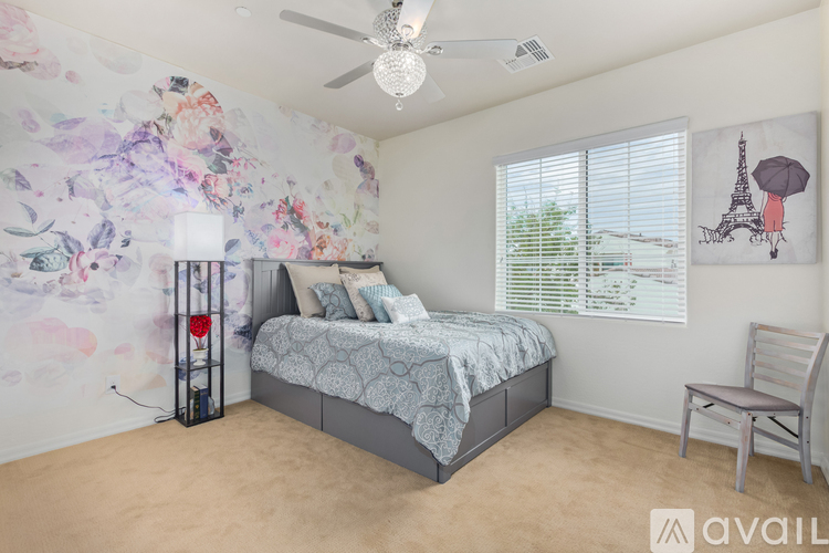 A bedroom with a bed, chair, and a wallpaper with a floral pattern.