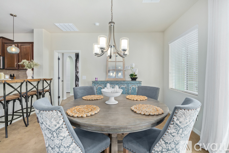 A dining room with a round table and grey chairs.