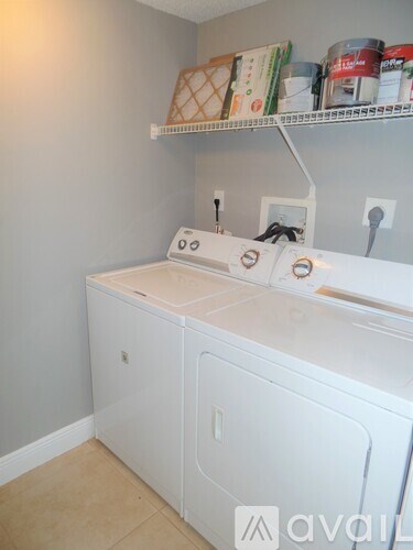 A white dishwasher is in a kitchen with a shelf above it.