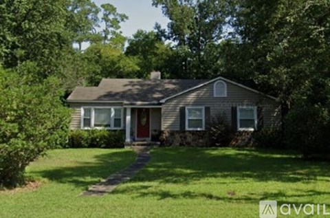 A house with a red door is surrounded by greenery.