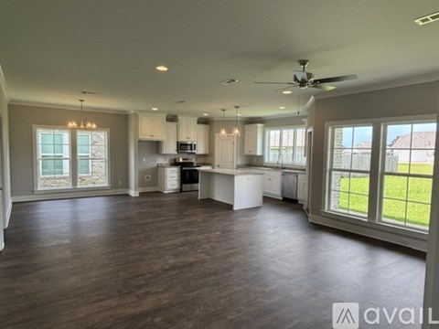 A spacious kitchen and living room with hardwood floors and large windows.