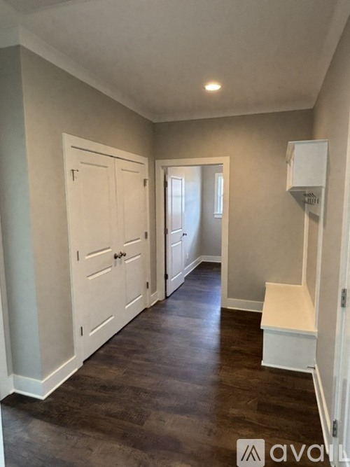 A hallway with a bench and a door.