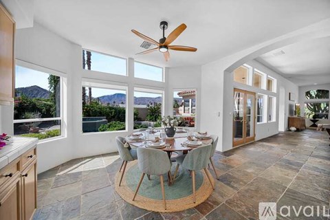 A dining room with a table set for six with a view of the mountains.