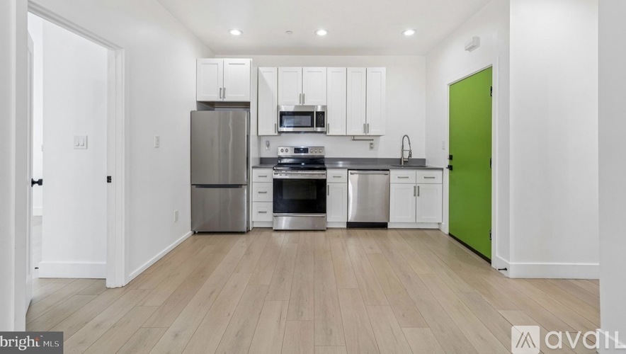 A kitchen with a green door and white walls.