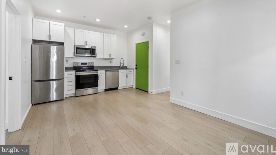 A kitchen with white cabinets and a green door.