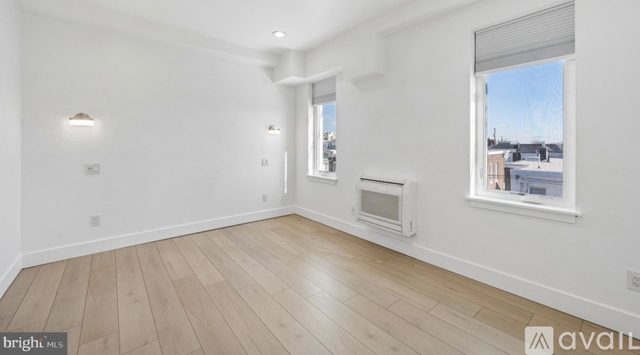 A spacious room with wooden flooring and white walls.