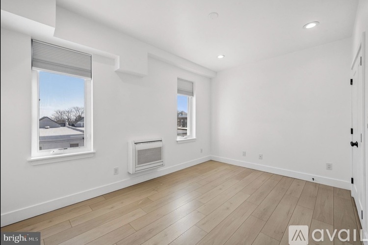 A bright, empty room with wooden floors and two windows.