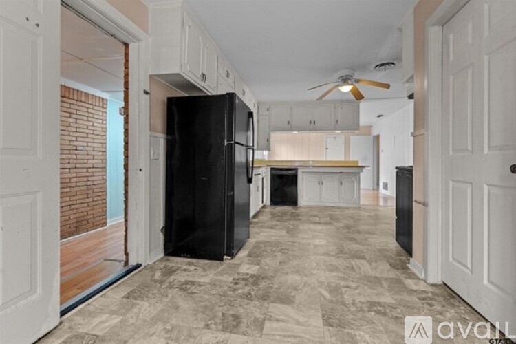 A kitchen with a black refrigerator and a ceiling fan.