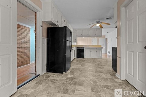 A kitchen with a black refrigerator and a ceiling fan.