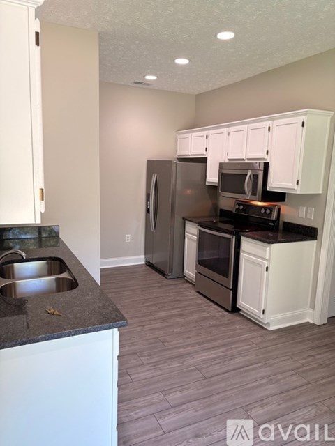A kitchen with white cabinets and a black countertop.