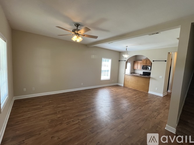 A spacious room with wood flooring and a ceiling fan.