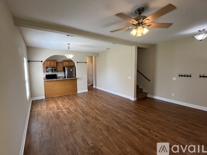 A spacious room with a ceiling fan and wooden flooring.