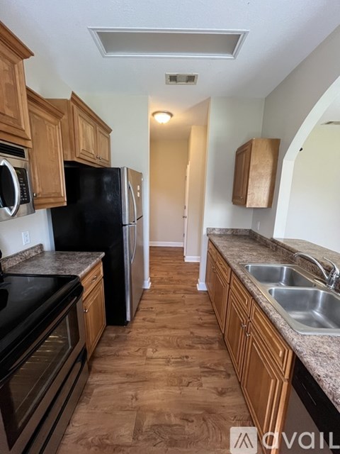 A kitchen with black appliances and wooden cabinets.