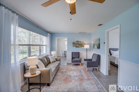 A living room with a beige couch, a rug, and a ceiling fan.