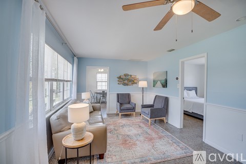 A living room with a ceiling fan and a rug on the floor.