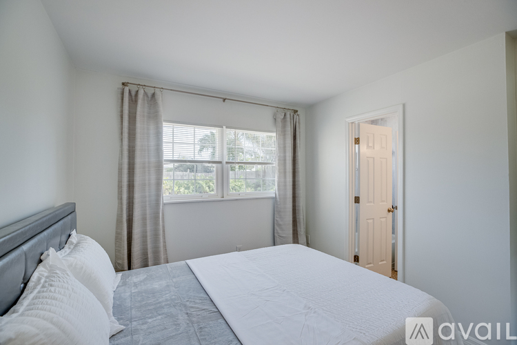 A bedroom with a large bed and a window with curtains.