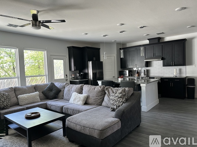 A modern living room with a grey sofa and a black ceiling fan.