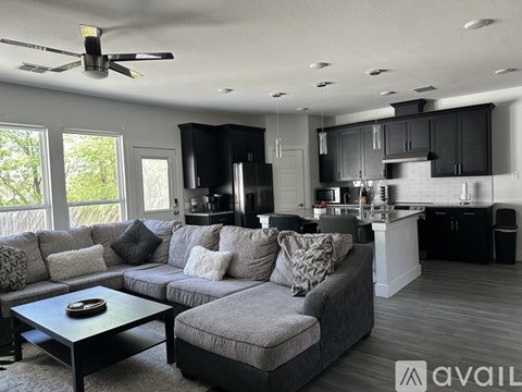 A modern living room with a grey sofa and a black ceiling fan.