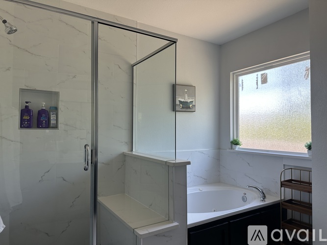 A bathroom with a glass shower door, a bathtub, and a window.