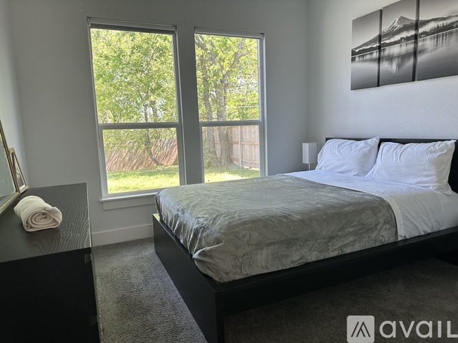 A bedroom with a large bed and a window overlooking a green area.